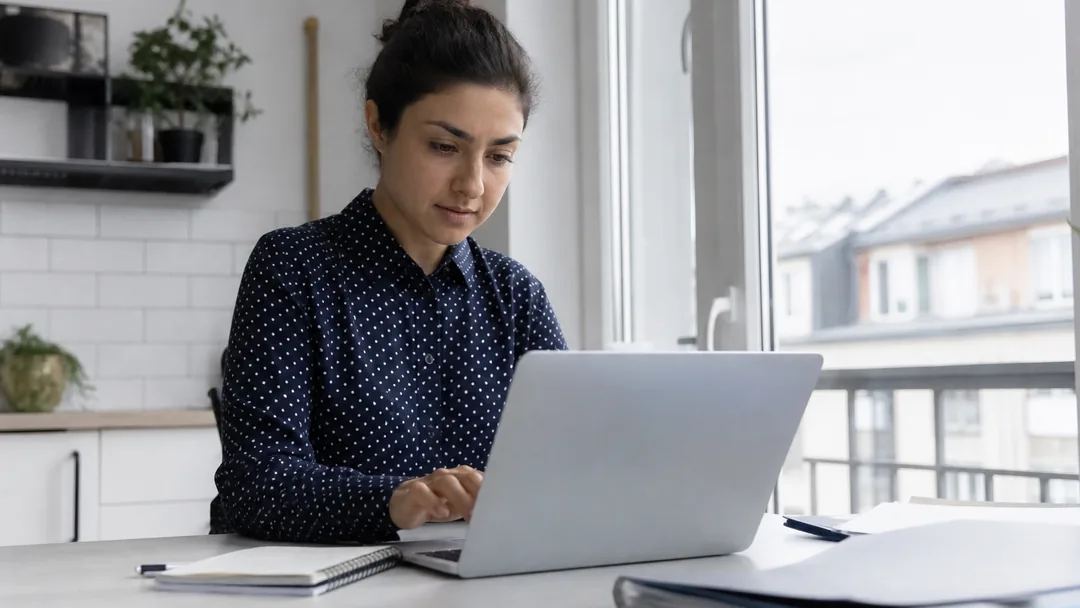 Eine Person sortiert Unterlagen und plant die nächsten Schritte am Laptop